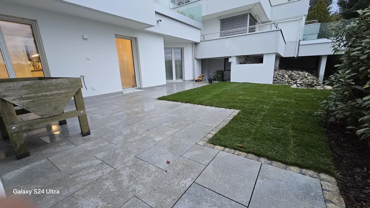 Sitzplatz aus Natursteinplatten mit angrenzender Rasenfläche in Pfäffikon – Soni Gartenbau