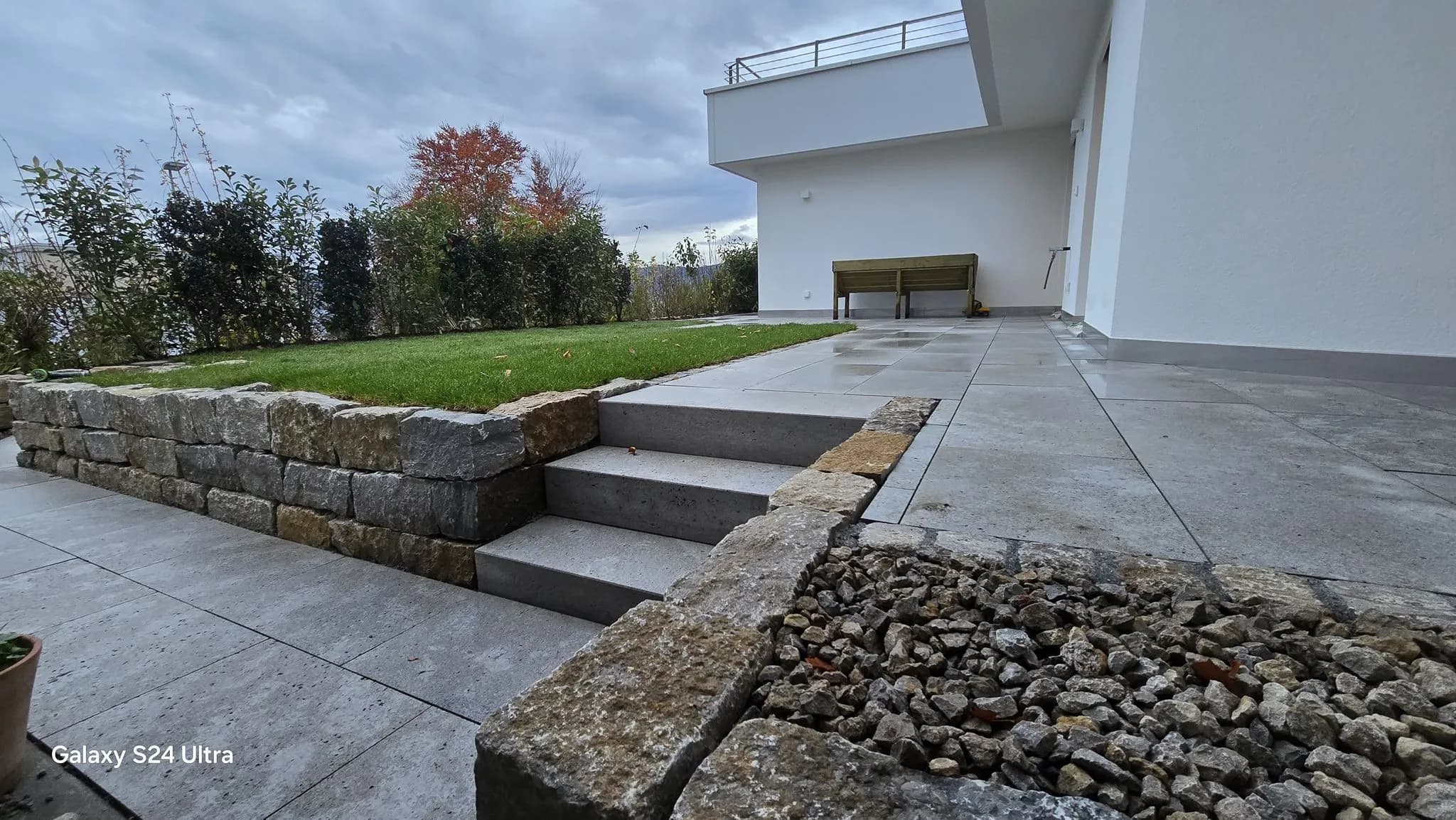 Natursteintreppe zwischen Plattenterrasse und Rasenfläche in Freienbach – Soni Gartenbau